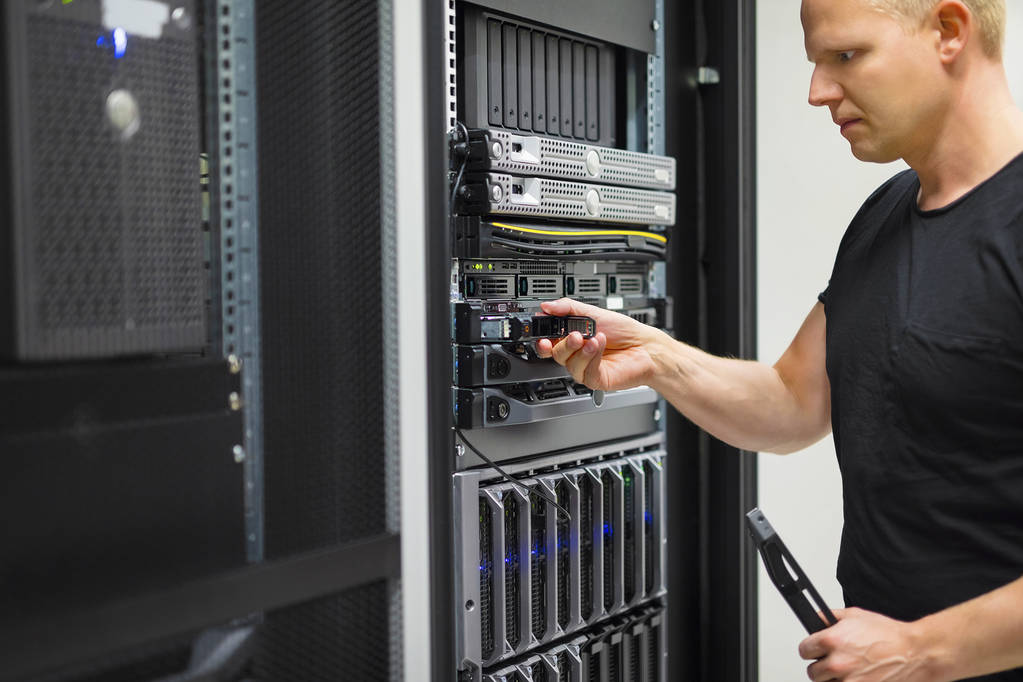 мужчина в дата центре хостинг провайдера с VPS серверами проверяет их работоспособность